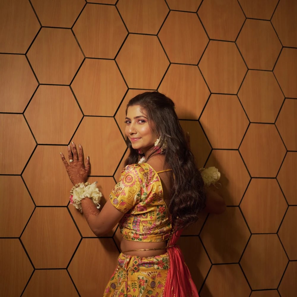 Woman in a colourful outfit beside a patterned wall