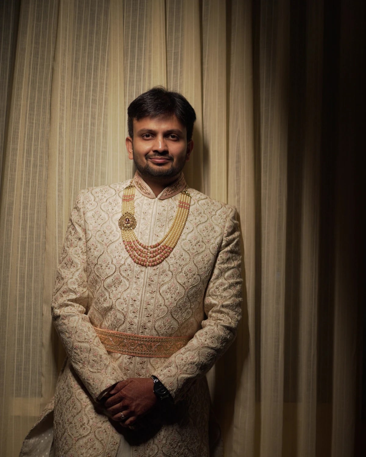 Man in traditional clothing beside curtains